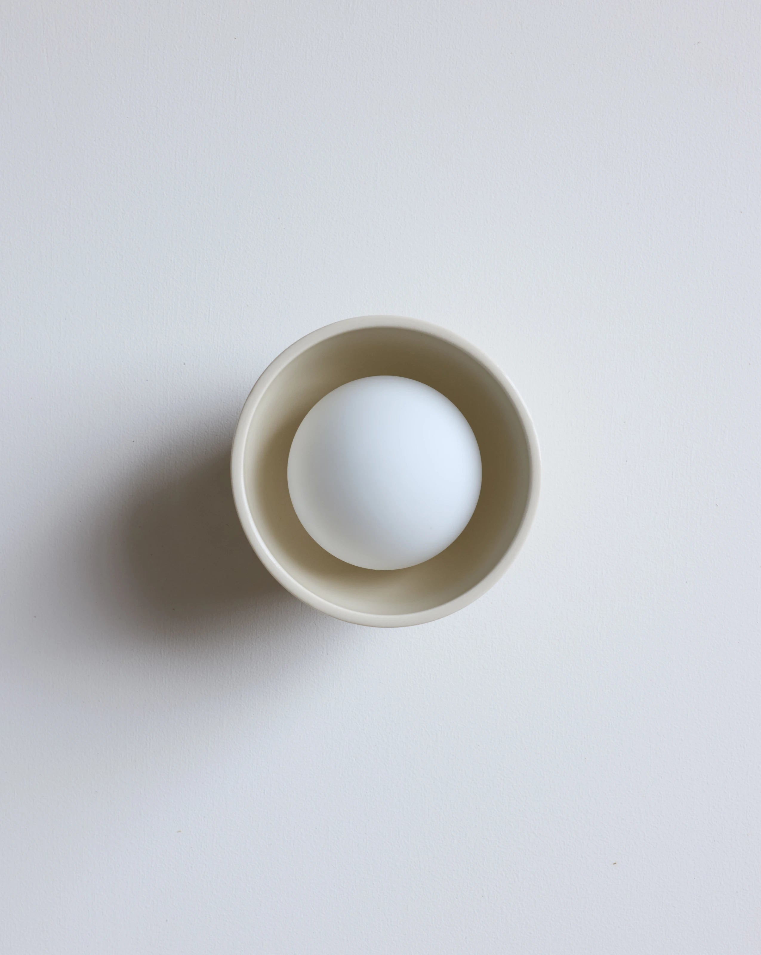 A cream lighting fixture on  a clean, light gray background.