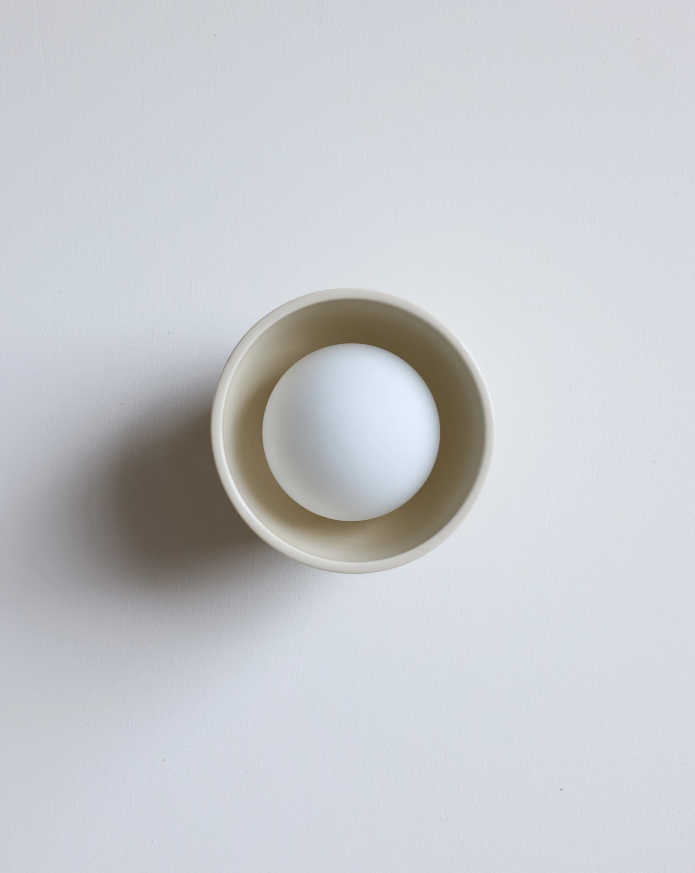 A cream lighting fixture on  a clean, light gray background.