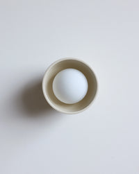 A cream lighting fixture on  a clean, light gray background.