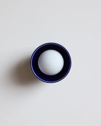 A dark navy ceramic wall sconce on a light gray background.