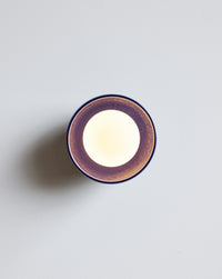 An illuminated dark navy wall sconce set against a plain light gray background.