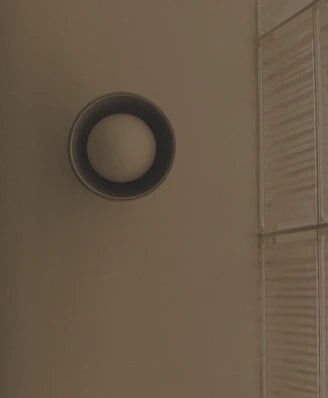 A round wall-mounted light fixture  mounted on a wall.